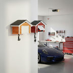 Decorative wall hooks shaped like small houses in a garage setting with a blue car.