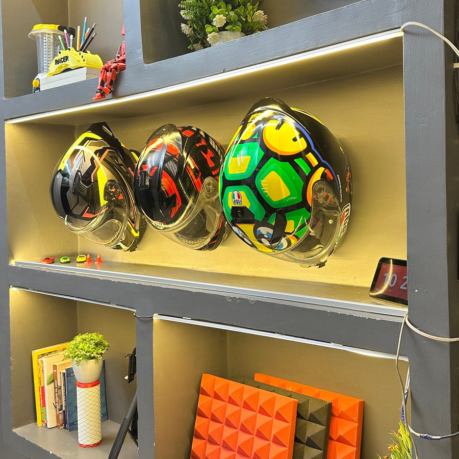 Shelving unit with colorful helmets, books, and decorative items on a gray wall.