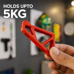 Red Helmet hanger hold  by a hand with text 'Holds upto 5KG' in a blurred indoor 