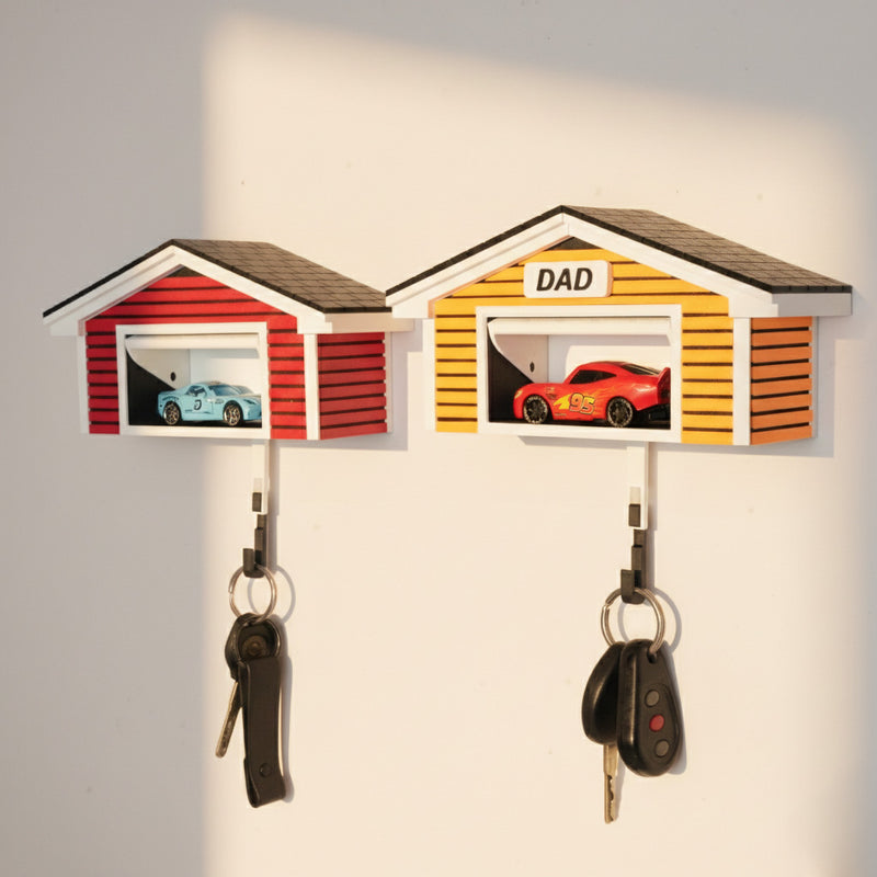 Wall-mounted key holder shaped like a garage with 'DAD' on top, featuring car-themed designs.