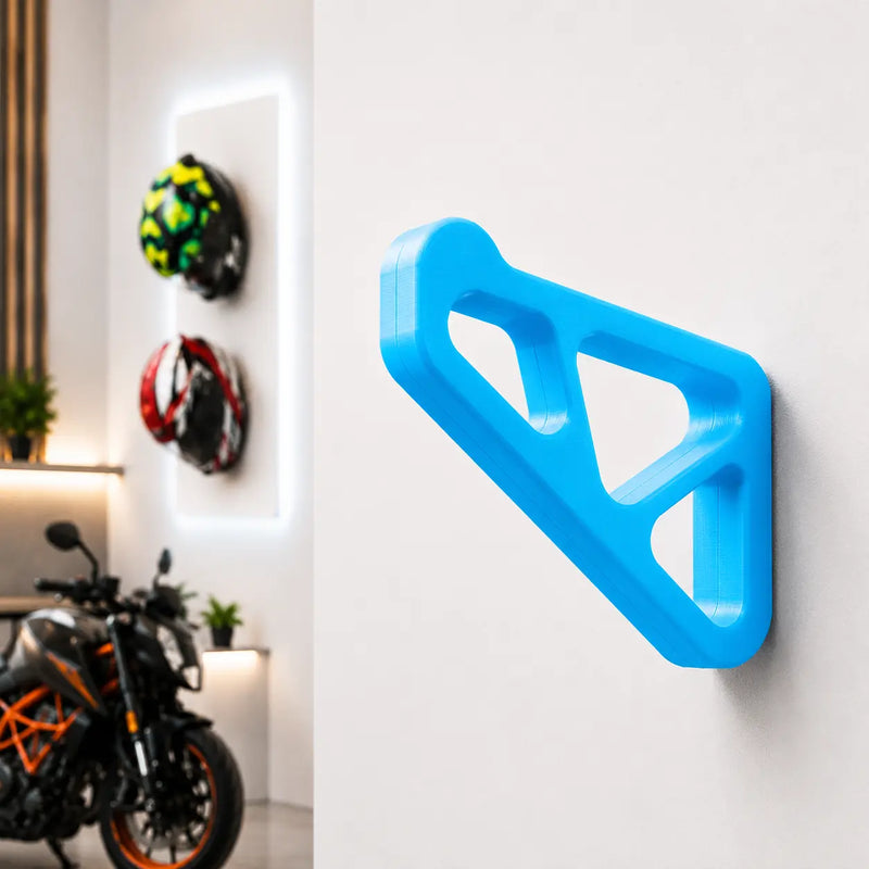 Dirt Accessories multi-color edition helmet hanger mounted on a garage wall, with blue accents and motorcycle helmets displayed in the background.