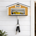 Decorative key holder shaped like a garage with a toy car inside, mounted on a wall.