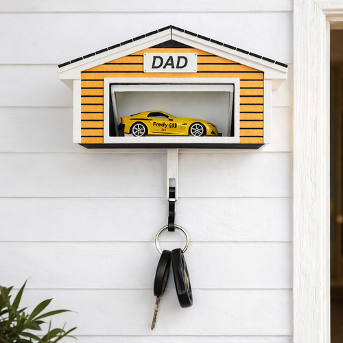 Decorative key holder shaped like a garage with a toy car inside, mounted on a wall.